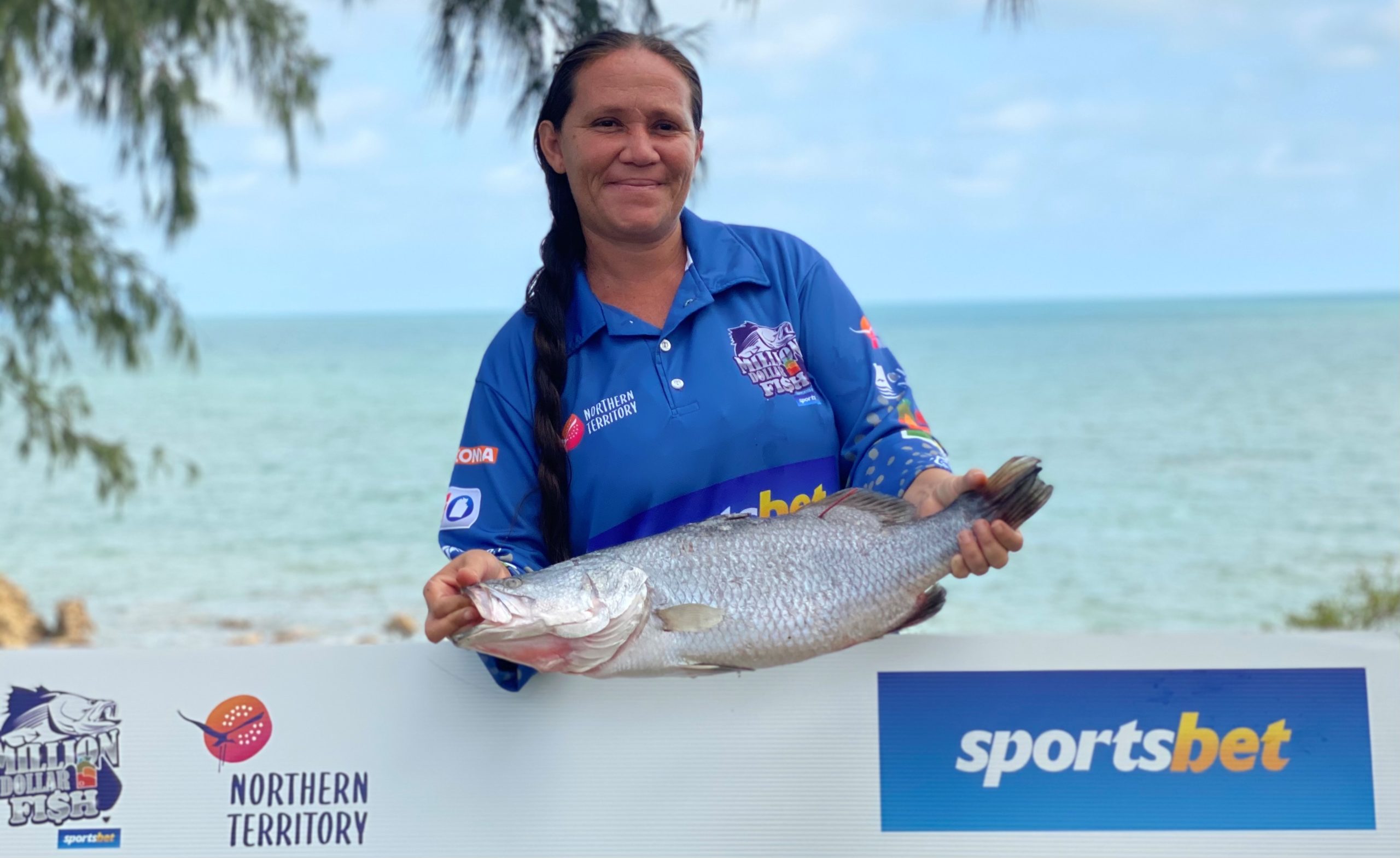 Female angler holding up $10,000 fish in front of cheque